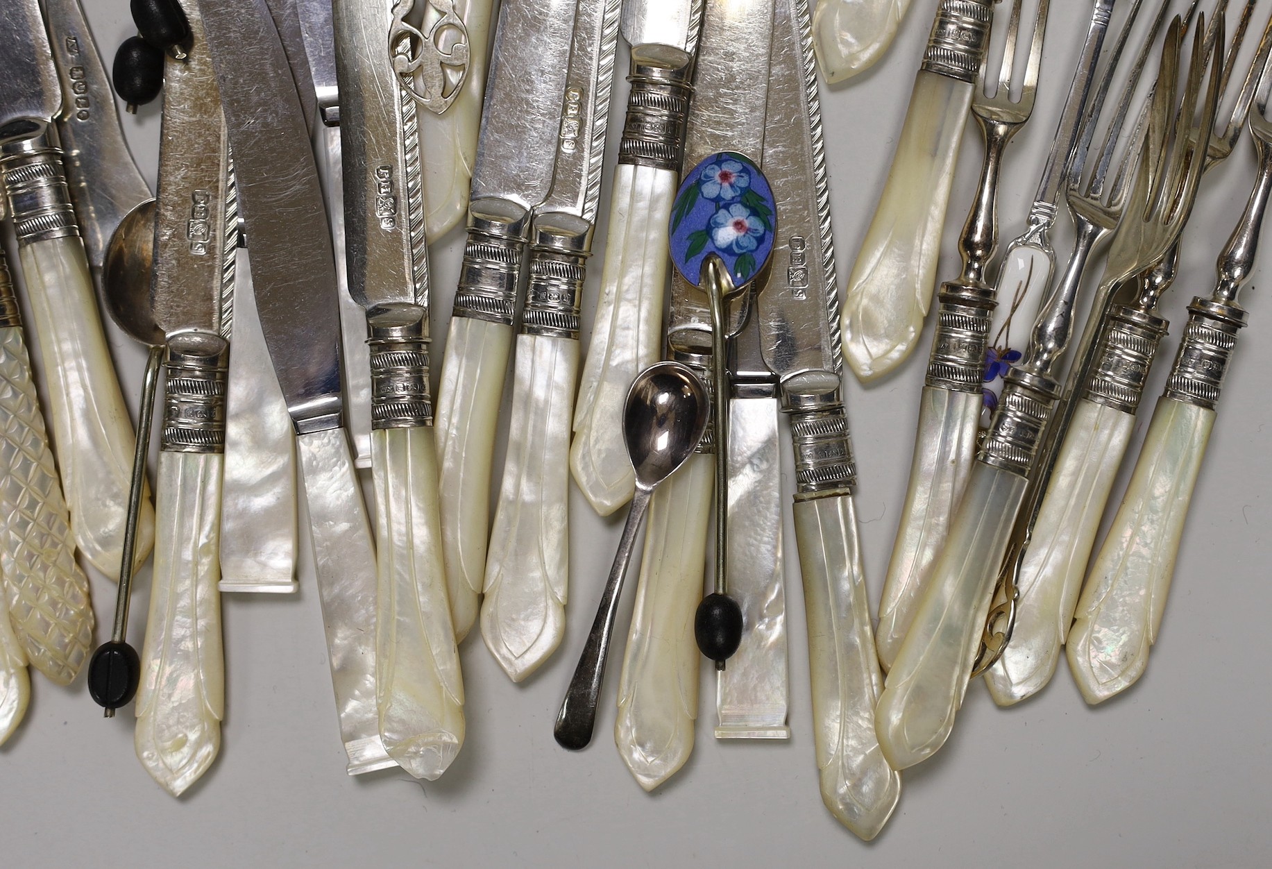 A selection of mounted mother-of-pearl knives and forks, together with finely decorated enamelled spoons
